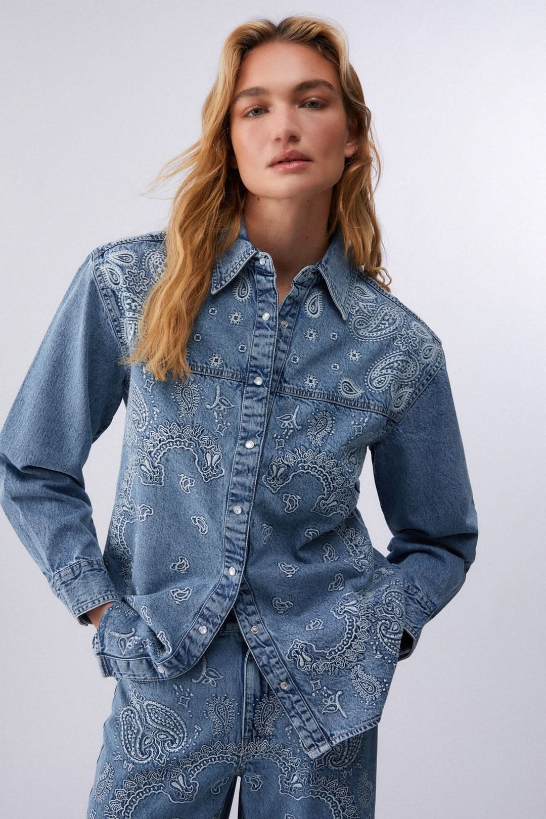 Veste en jean imprimée à boutons pression avec motif audacieux, portée par mannequin. Denim confortable et coupe classique.