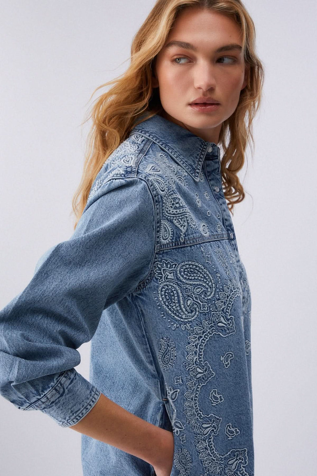 Veste en jean imprimée à boutons pression avec motif audacieux et moderne, portée par mannequin de profil en denim souple et confortable.