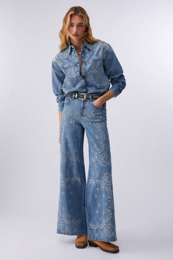 Modèle portant une veste en jean imprimée à boutons pression coupe droite avec motif audacieux, denim souple et confortable.