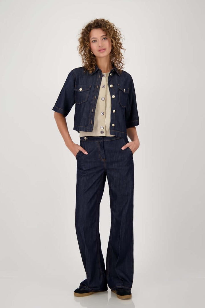 Femme portant une veste en jean courte avec manches évasées et un pantalon jeans, style casual-chic.