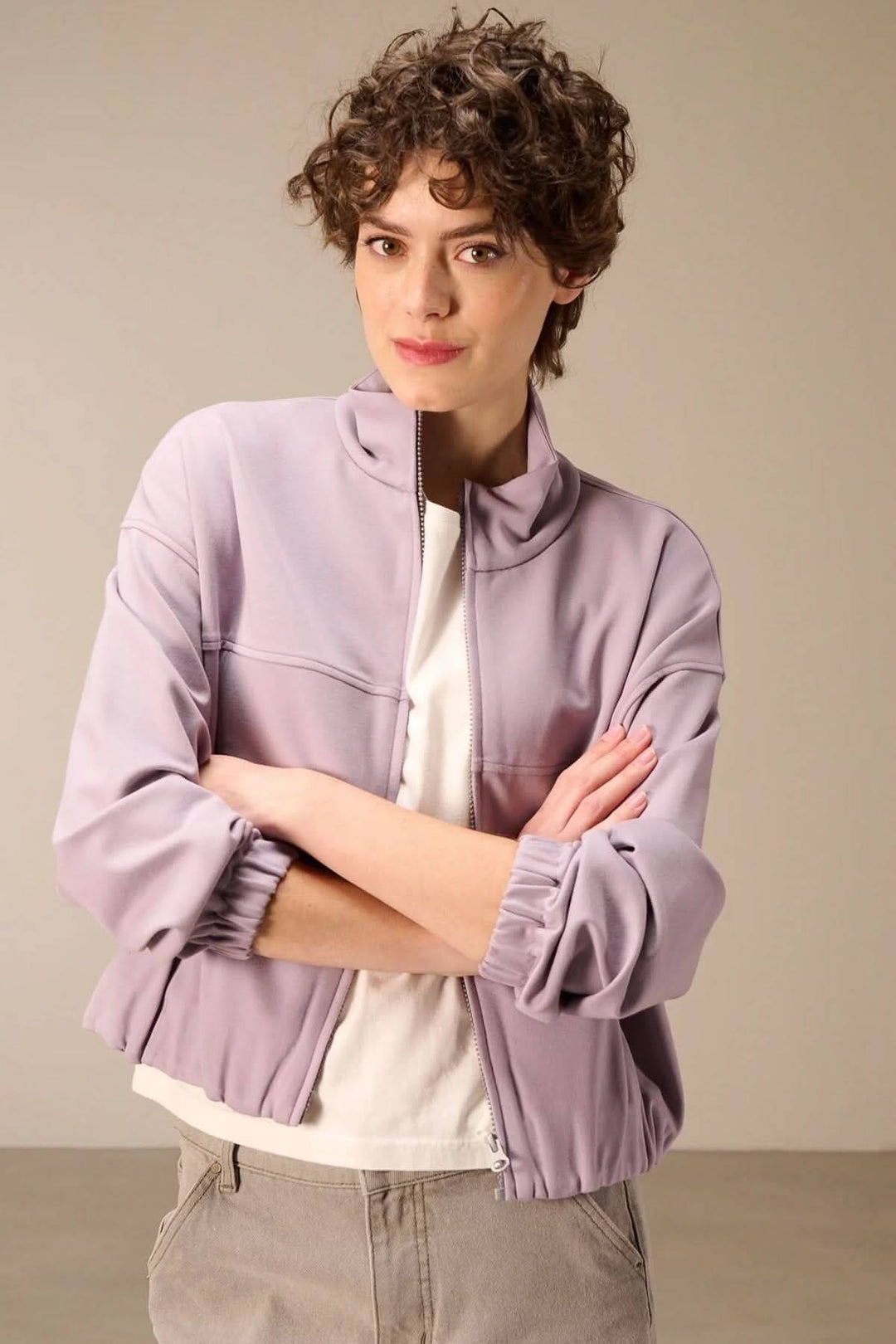 Veste en sweat avec fermeture éclair en mauve, portée par une femme, idéal pour un look décontracté mi-saison.