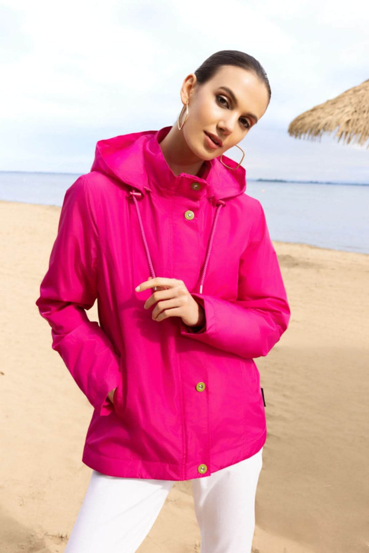 Femme portant une veste légère à capuche rose sur la plage, idéale pour les journées changeantes et les escapades en plein air.