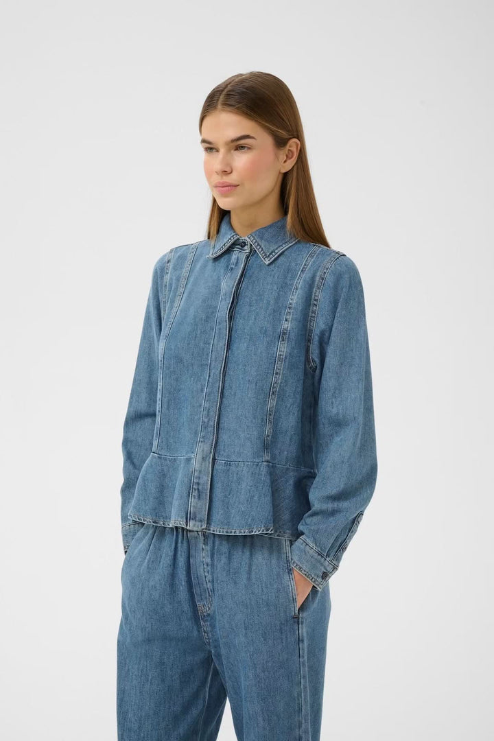 Veste légère zippée Sophina en jean portée par une femme, coupe épurée et moderne avec fermeture à glissière sur le devant.