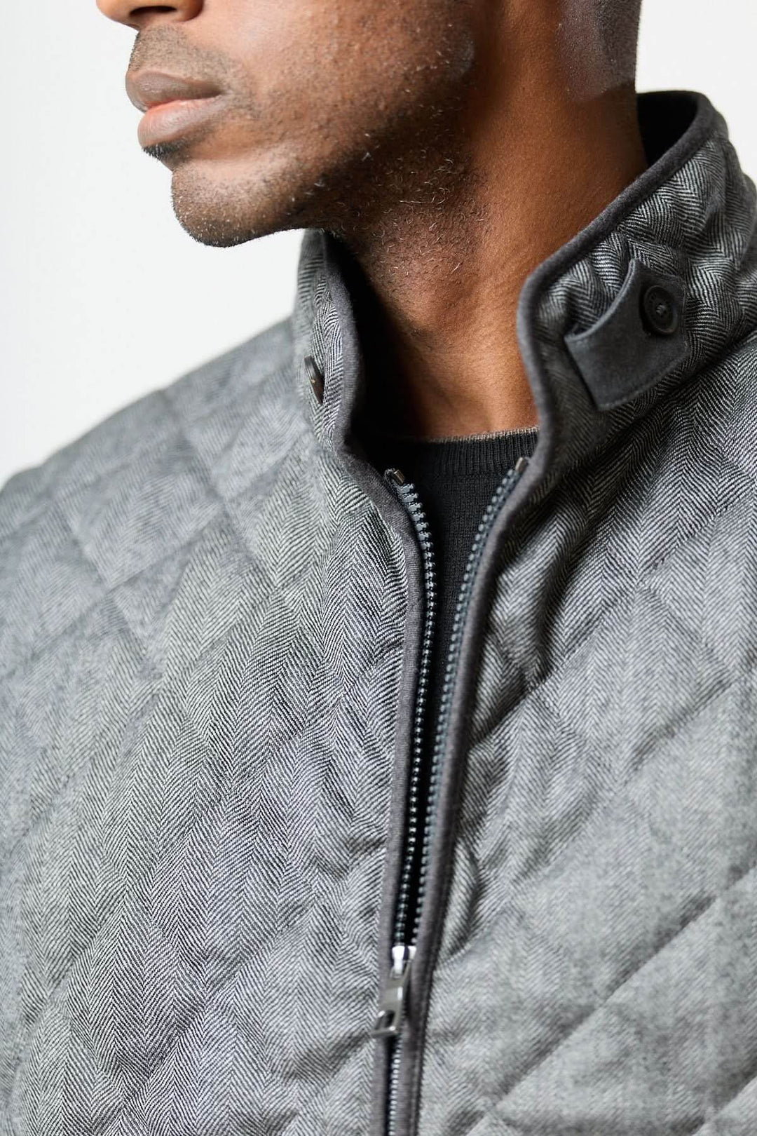 Veste sans manches matelassée en laine à motif chevrons avec col montant et fermeture zippée, élégance urbaine et chaleur assurée.