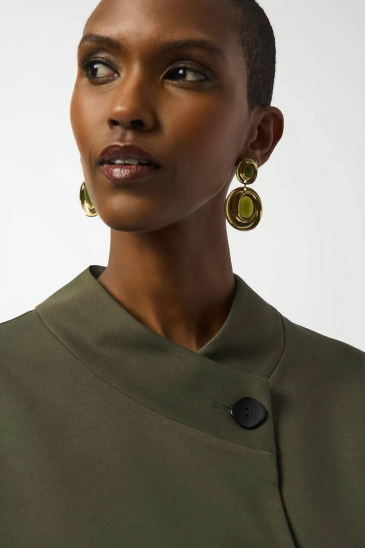 Veste style cape à col drapé en vert olive, modèle féminin avec gros bouton noir.