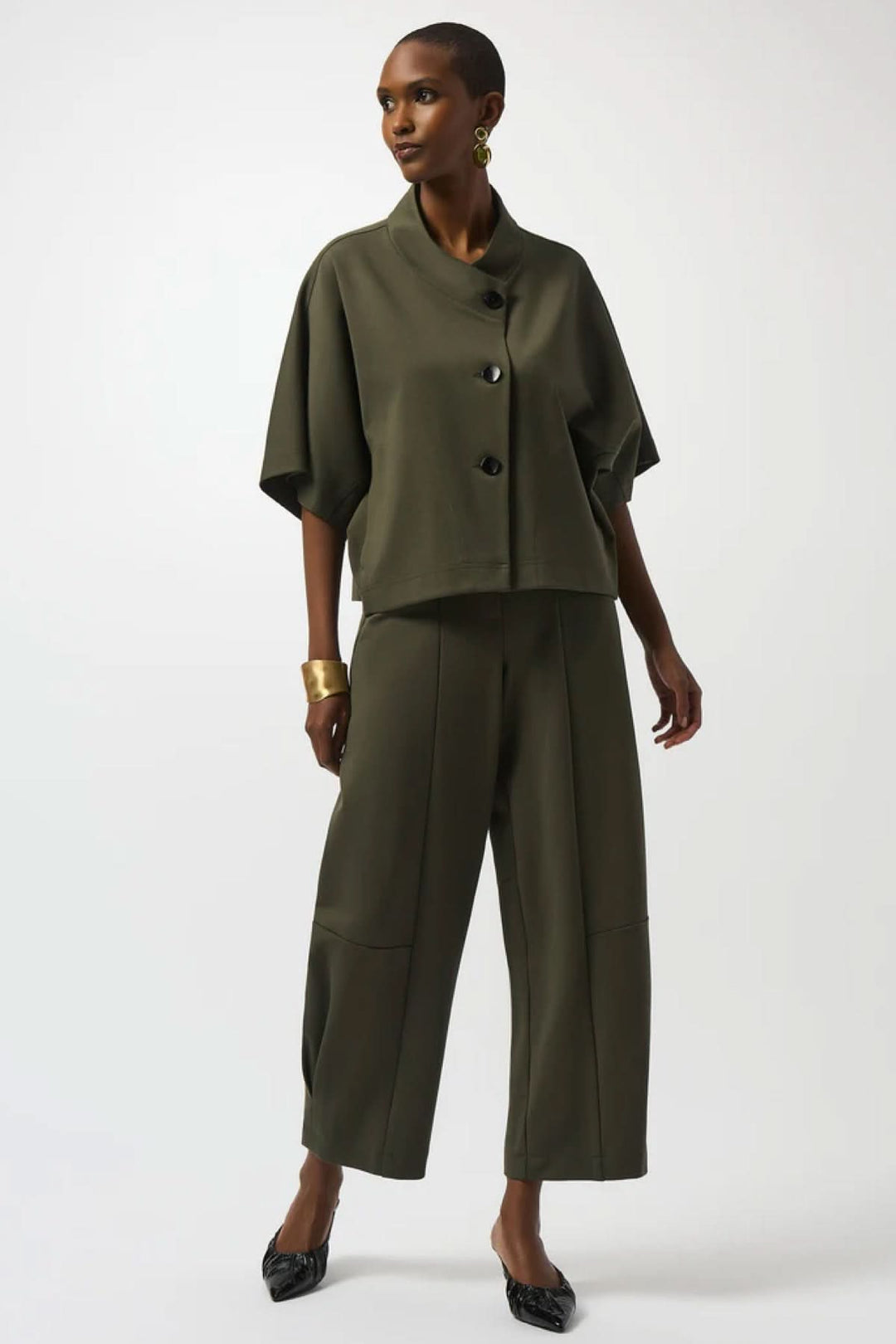 Veste style cape à manches courtes en vert olive, col large drapé, fermeture avec boutons noirs, tenue moderne.