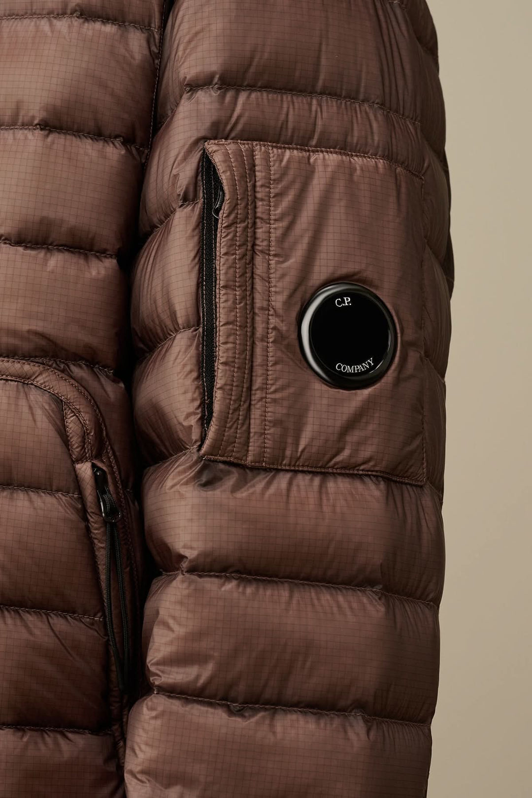 Zoom sur une doudoune brune avec poche zippée et détail de lentille, en tissu léger D.D. Shell.