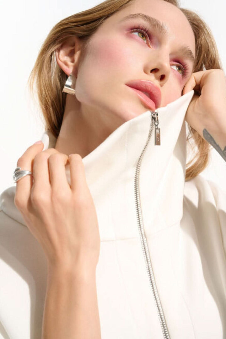 Femme portant une veste zippée à col large en blanc, illustrant l&