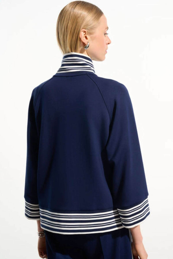 Femme portant une veste zippée à rayures contrastantes avec col et poignets rayés, vue de dos, style décontracté chic.