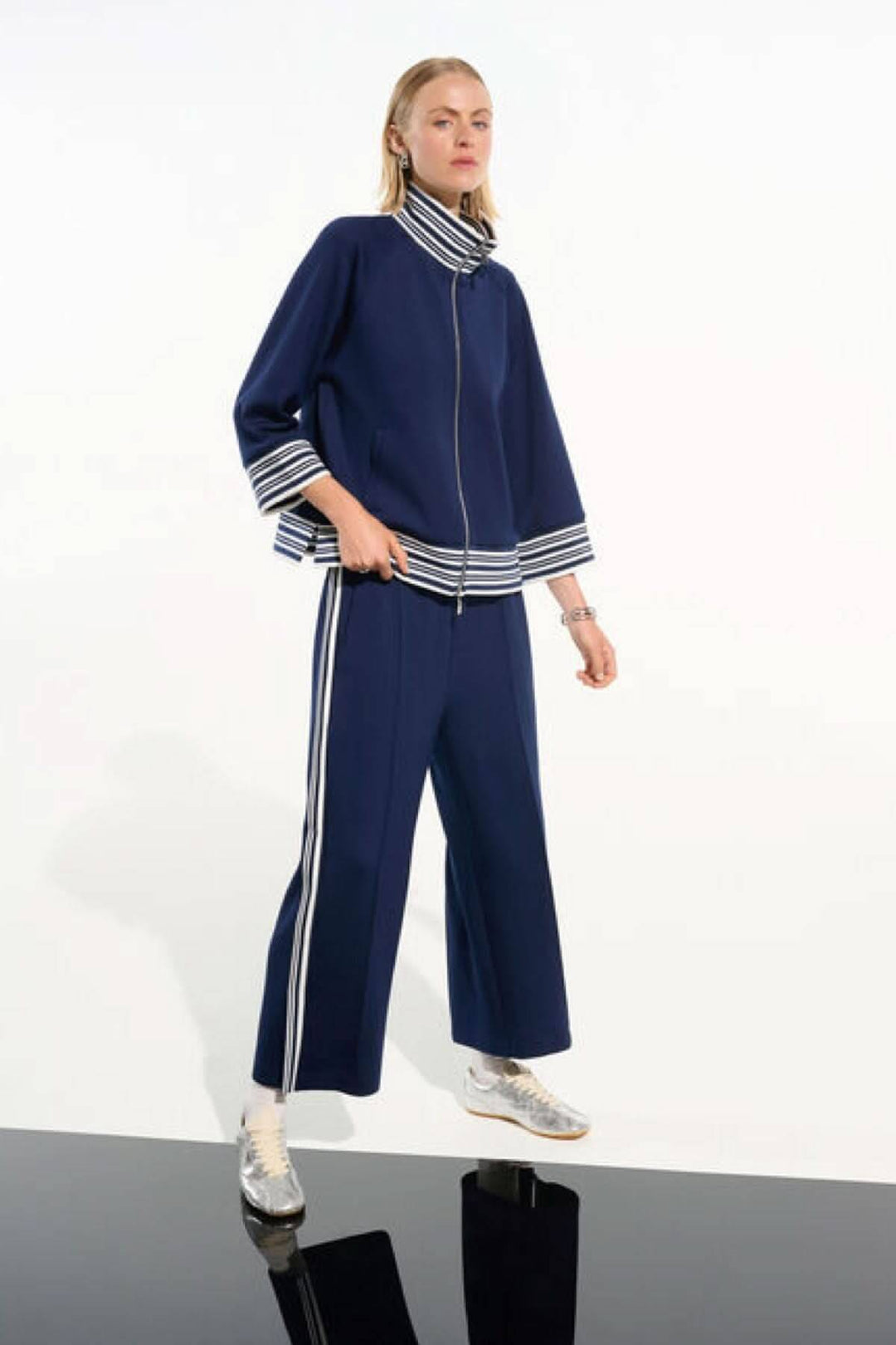 Femme portant une veste zippée à rayures contrastantes avec col et poignets à rayures, style décontracté et chic.