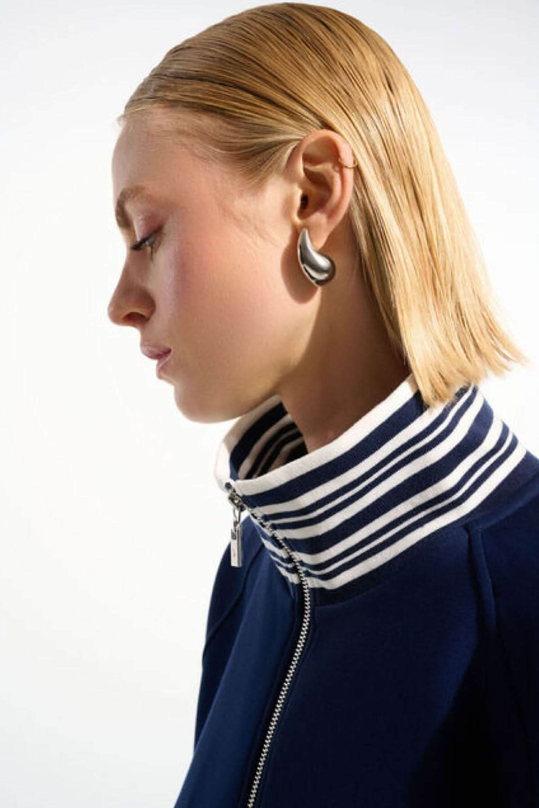 Modèle portant une veste zippée à rayures contrastantes avec finition au col, style chic et décontracté.