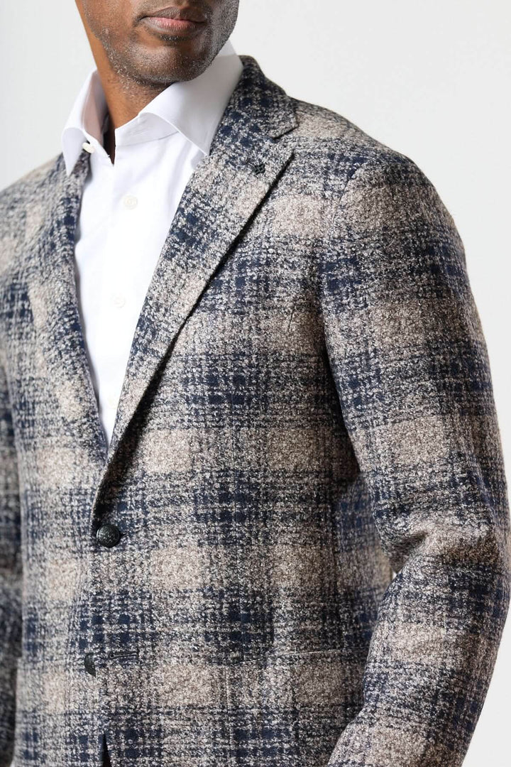 Homme portant un veston à carreaux brossé deux boutons, sans épaulettes, avec une chemise blanche pour un look urbain soigné.