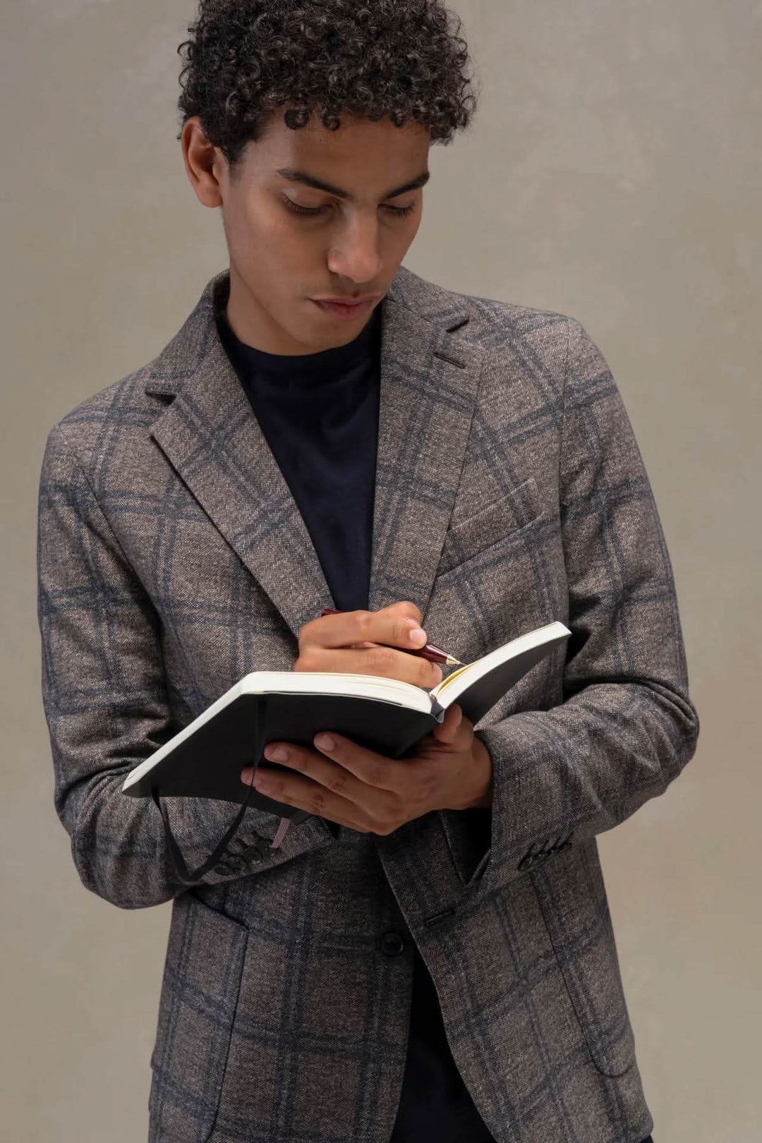 Homme portant un veston à carreaux coton extensible écrivant dans un carnet.