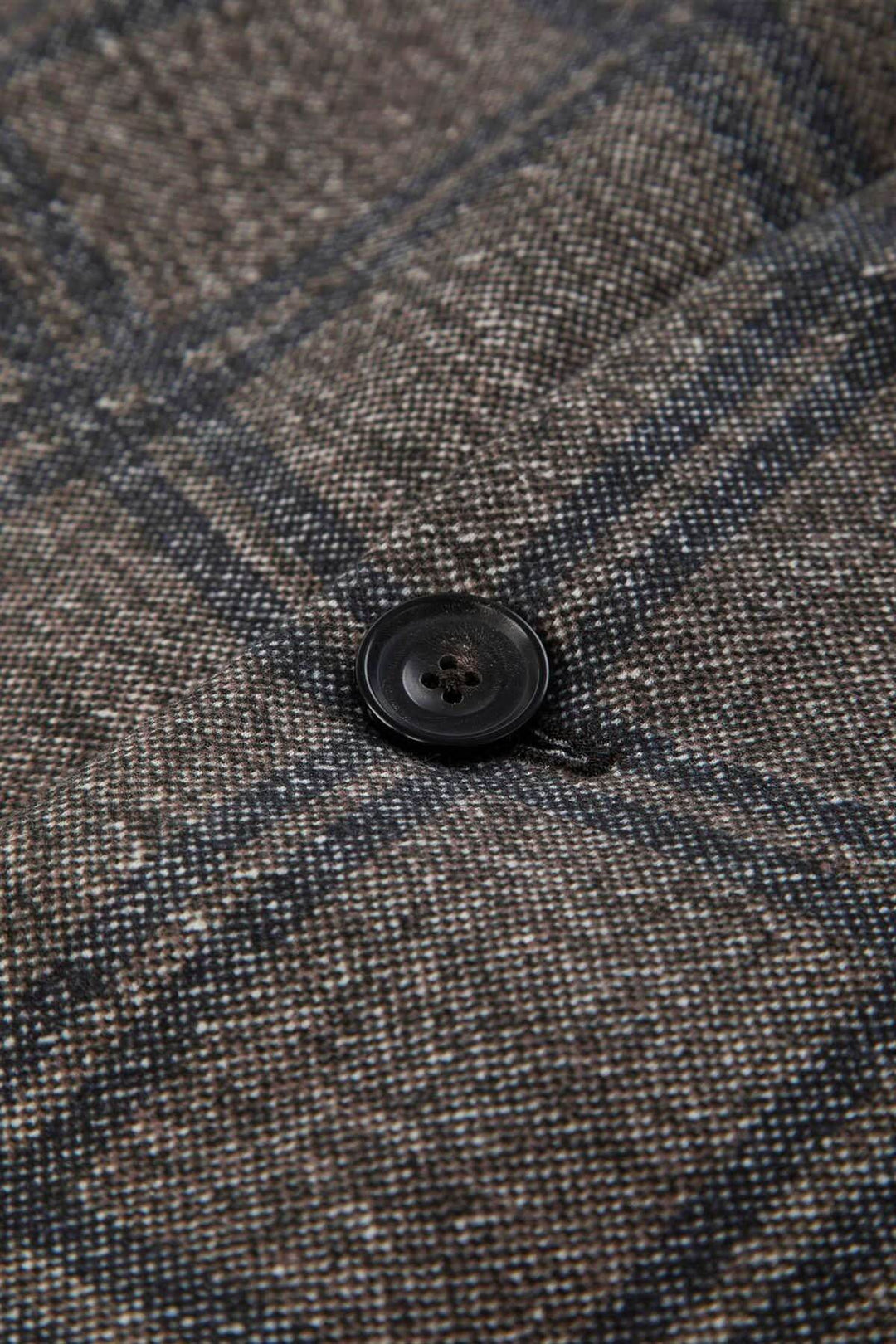 Gros plan sur un bouton du veston à carreaux coton extensible montrant le motif élégant et la texture douce.
