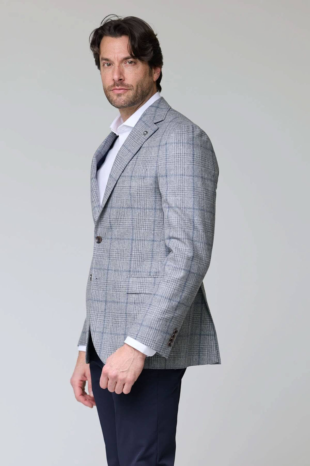 Homme portant un veston à carreaux moderne avec une coupe ajustée, idéal pour un style élégant et sophistiqué au bureau ou en soirée.