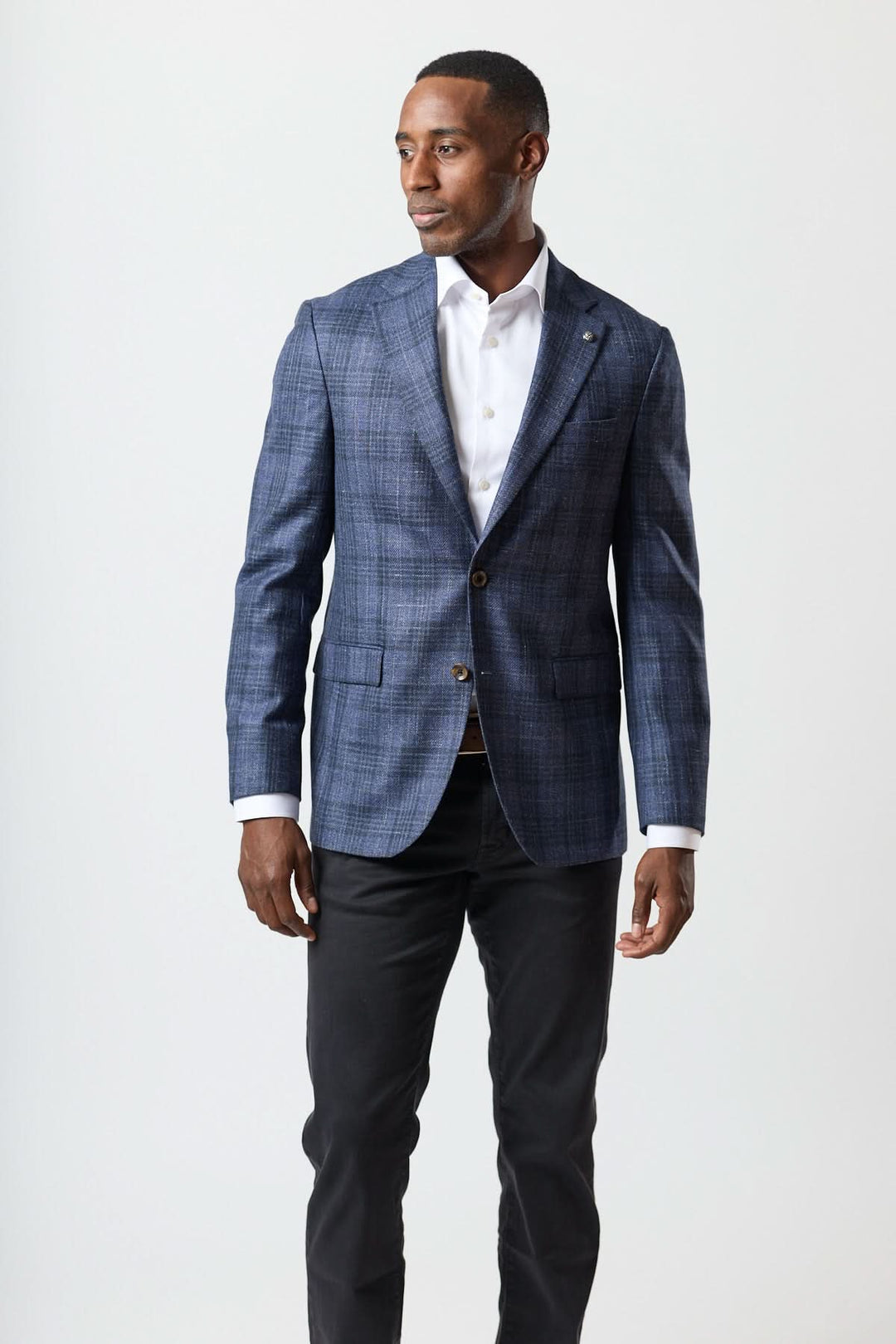 Homme portant un veston à carreaux texturé deux boutons avec chemise blanche et pantalon noir.