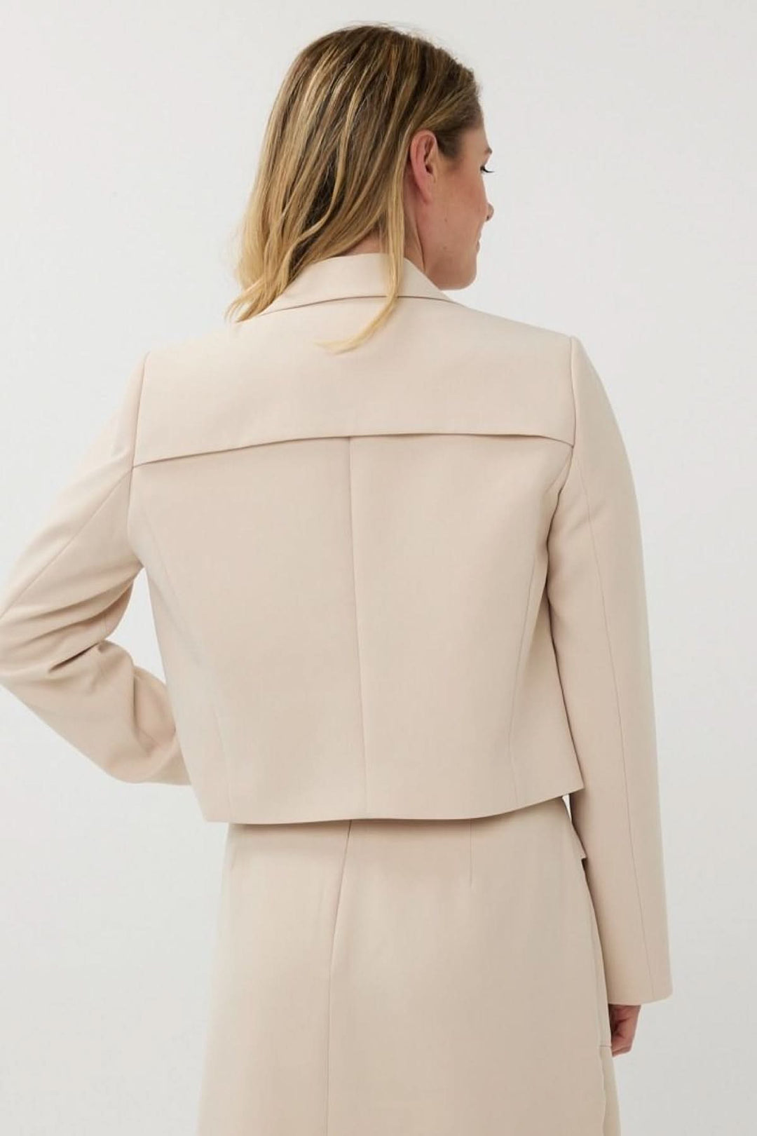 Détail arrière d'un veston court structuré, moderne et féminin, porté par une femme.
