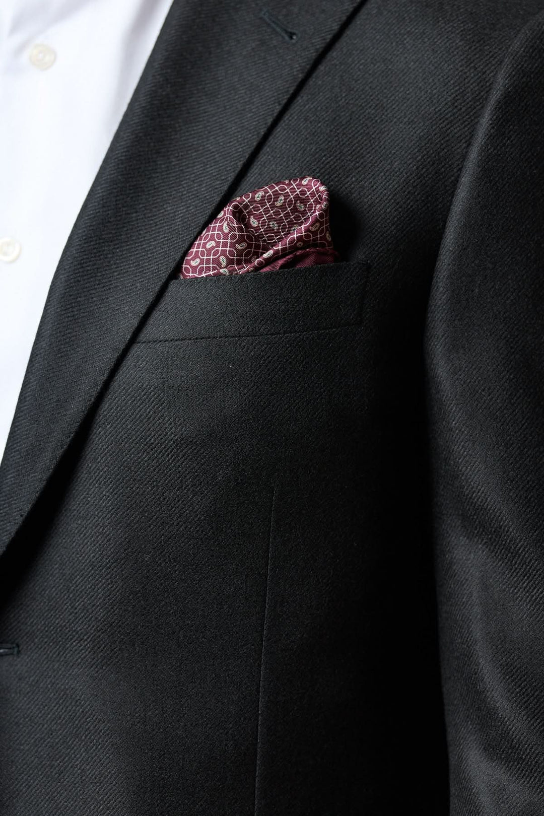 Veston en laine et cachemire noir avec texture satinée et pochette rouge, élégance italienne formelle.