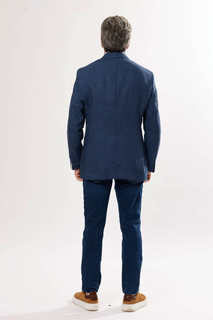 Homme portant un veston en lin bleu, vu de dos, avec un pantalon assorti et des chaussures décontractées.