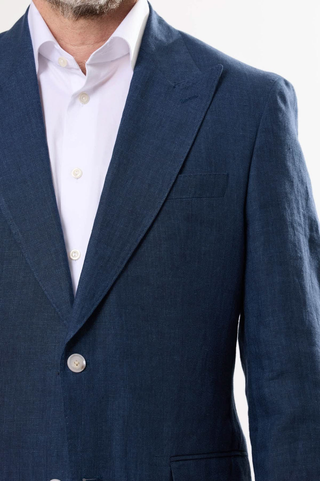 Veston en lin bleu élégant pour homme, fermé avec des boutons, porté sur une chemise blanche.