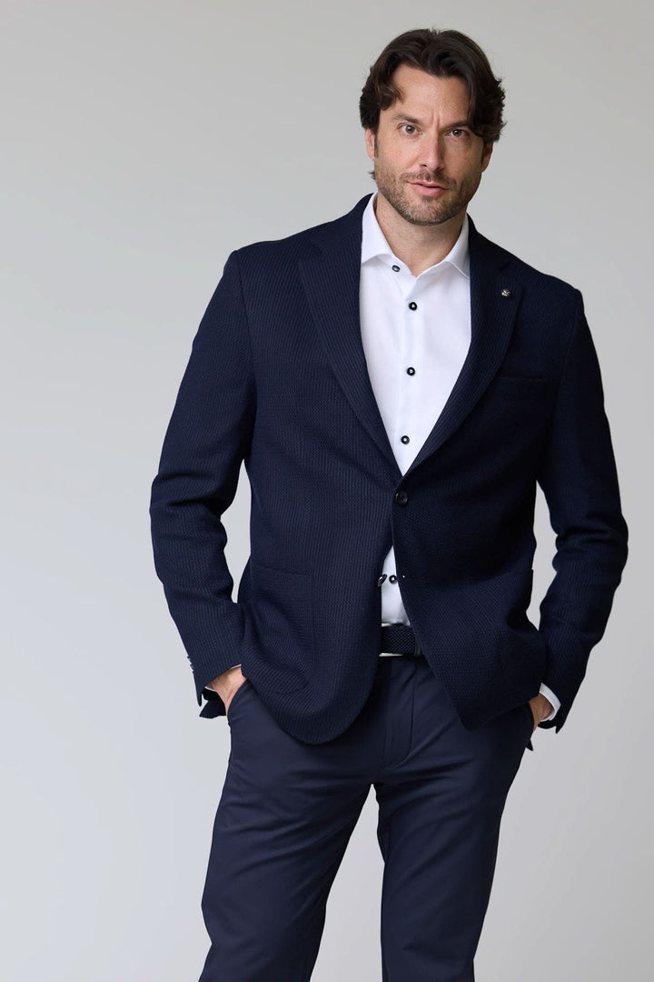 Veston en tricot structuré, élégant et confortable, porté avec une chemise blanche pour un style moderne.