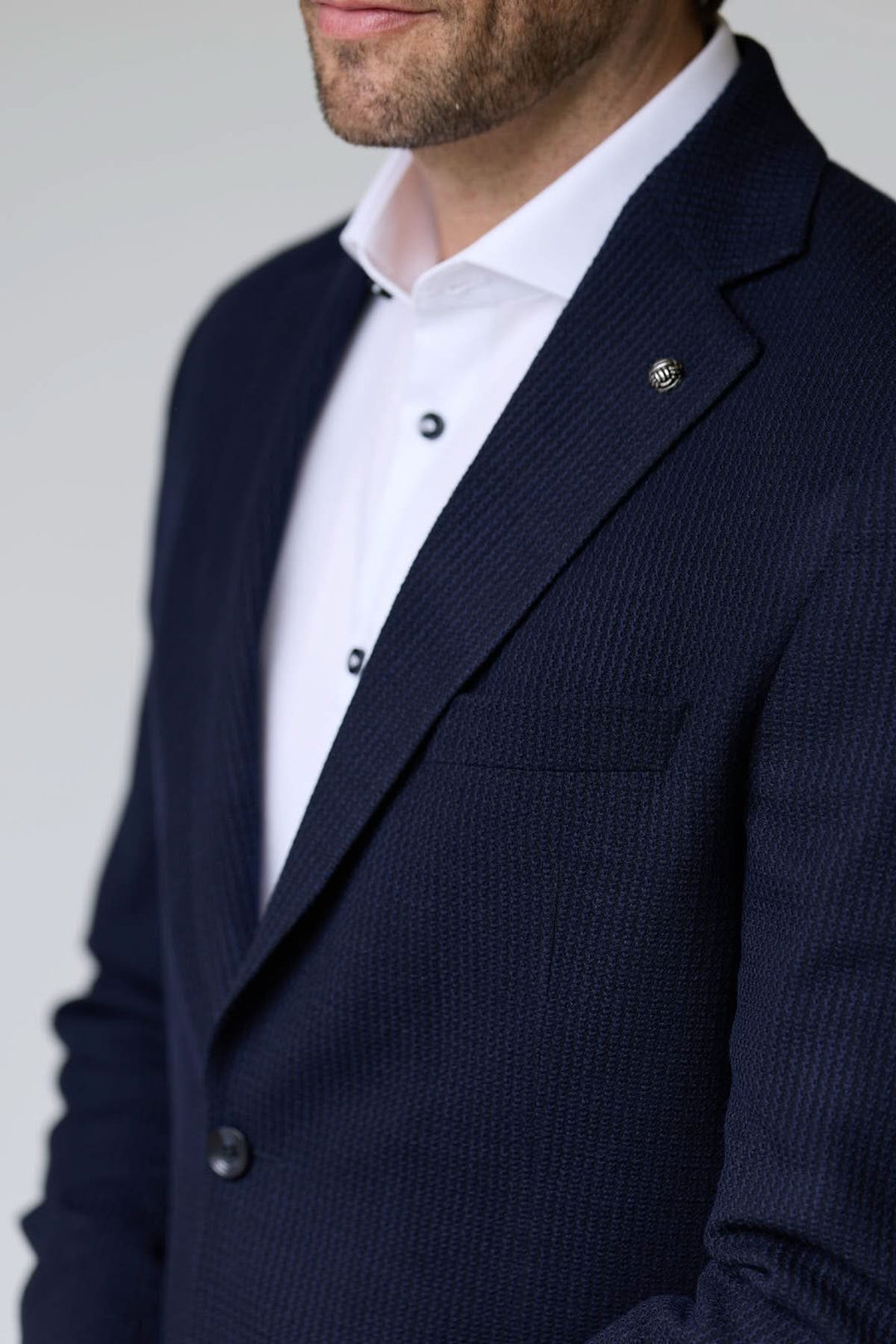Veston en tricot structuré porté avec une chemise blanche, offrant élégance et confort grâce à sa matière texturée et souple.