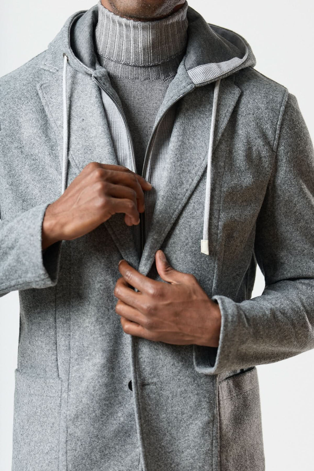Veston hybride à capuche gris avec fermeture deux boutons porté sur un col roulé pour un style urbain élégant.