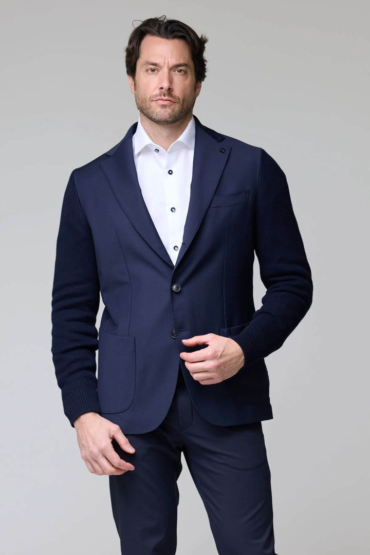 Veston hybride tricot et tissu bleu élégant sur un homme, alliant style moderne avec manches en maille et col à revers classique.