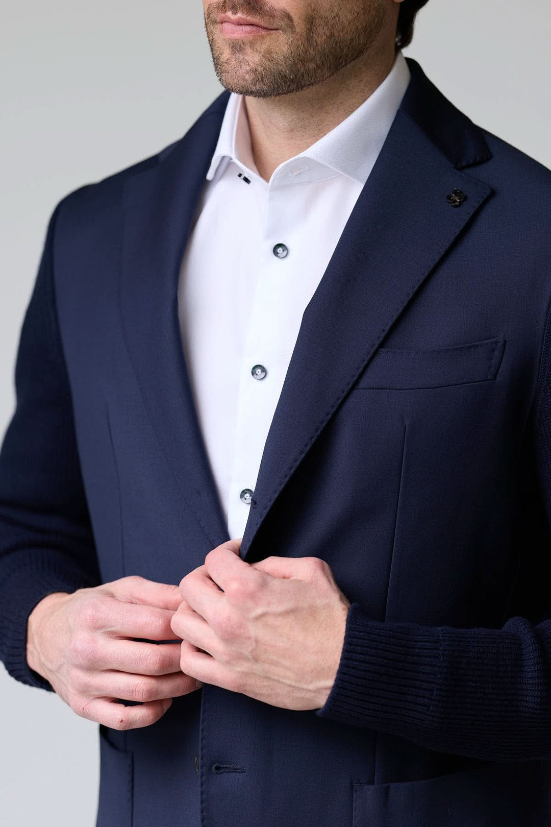 Homme portant un veston hybride tricot et tissu avec manches en maille et col à revers classique, look chic et décontracté.