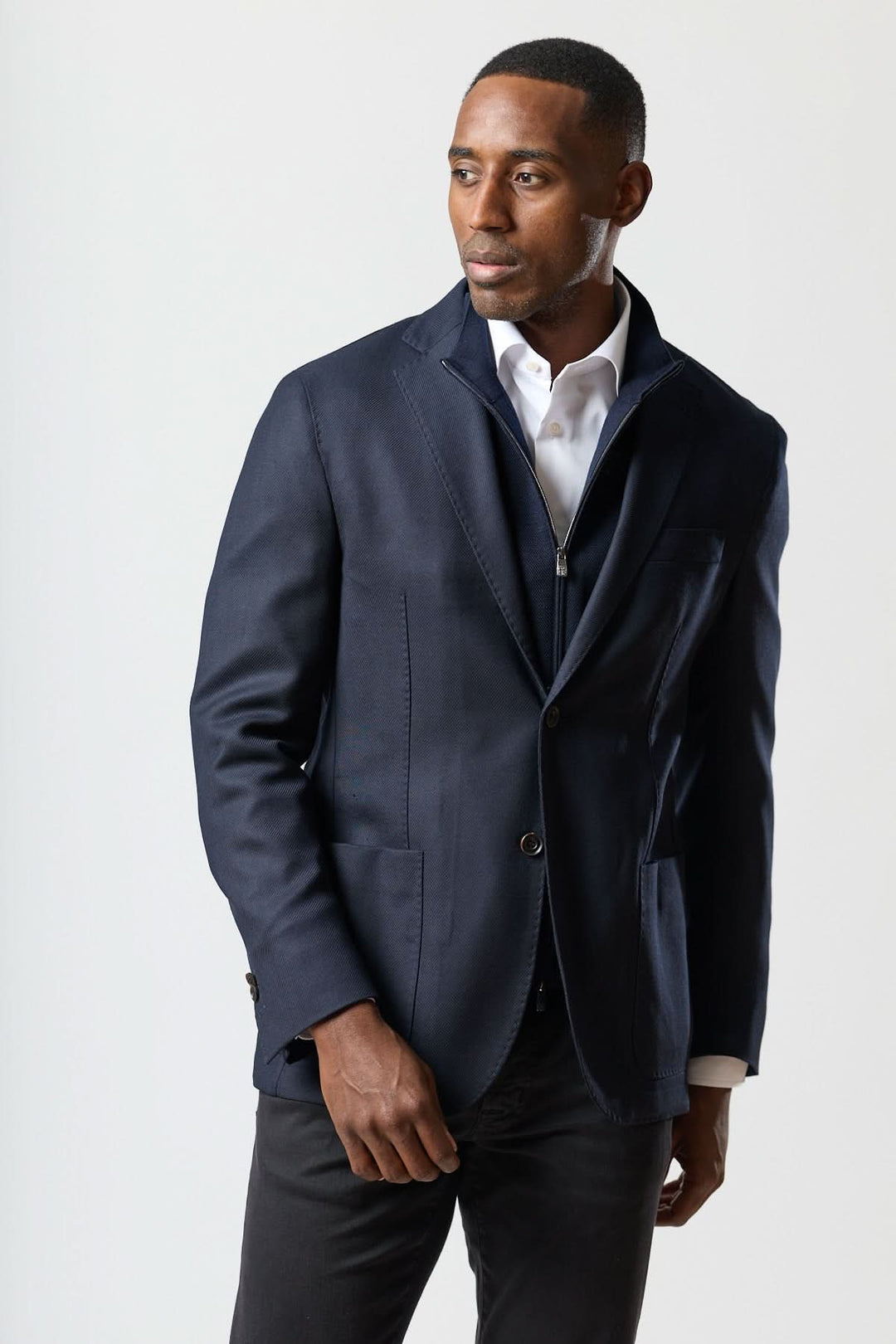 Homme portant un veston moderne avec gilet zippé intégré, coupe semi-ajustée et élégante, style contemporain.