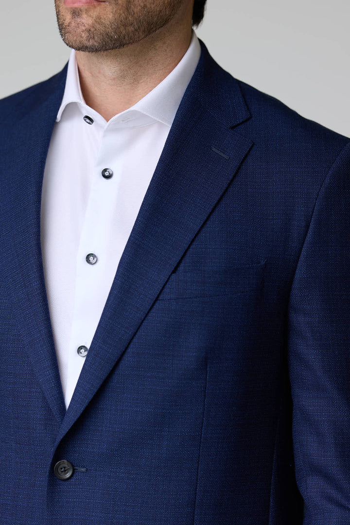 Homme portant un veston structuré à micro motif élégant et moderne.