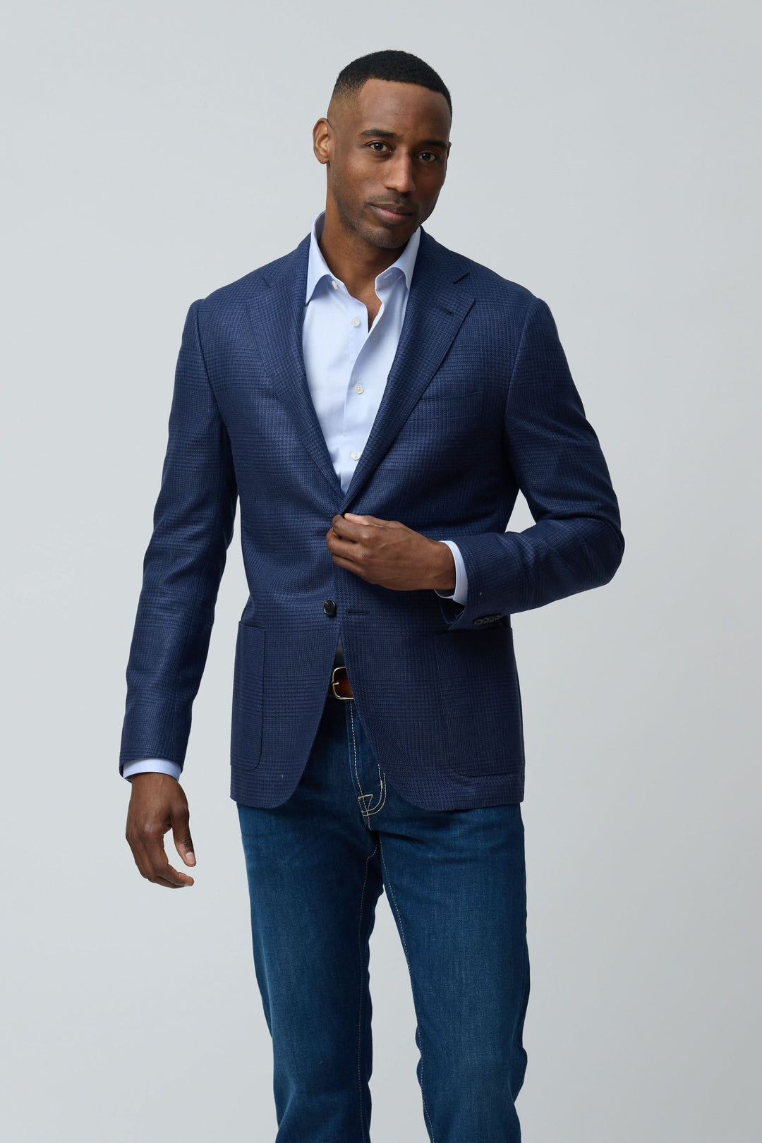 Homme portant un veston structuré à motif subtil avec chemise blanche et jean.
