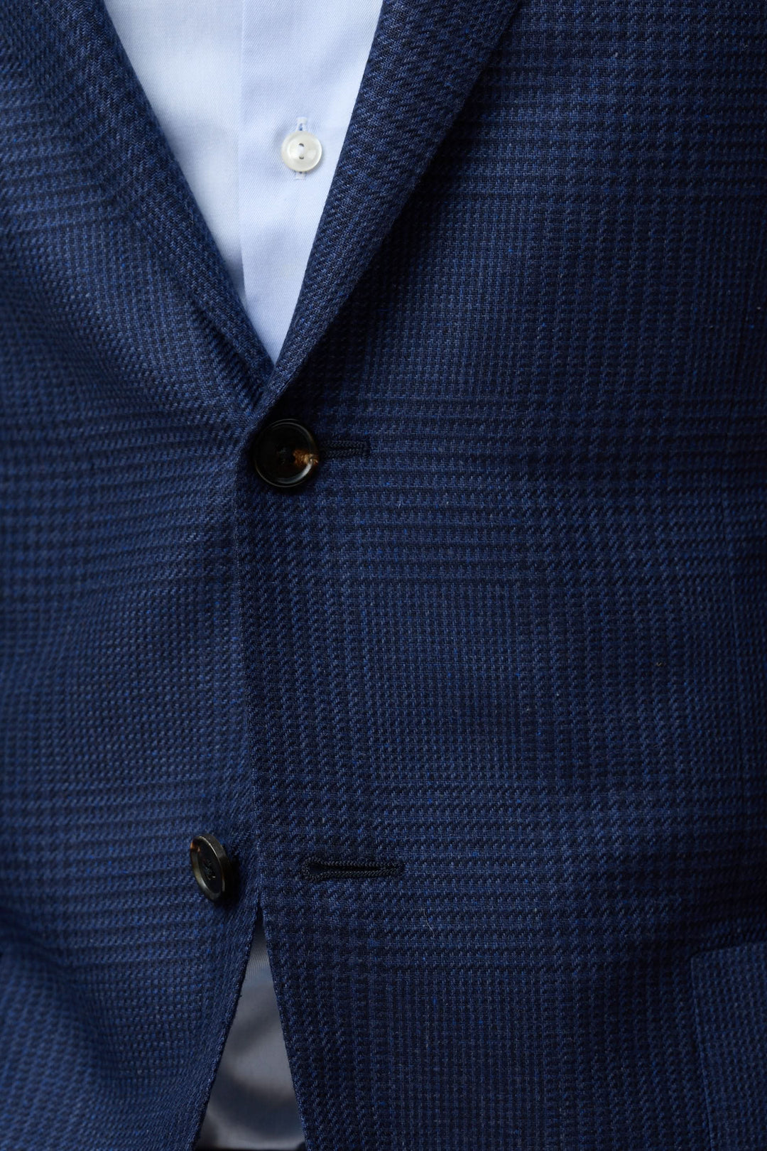 Veston structuré à motif subtil en tissu texturé bleu avec une fermeture à deux boutons et revers classiques.