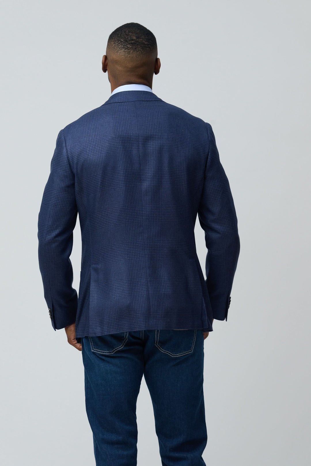 Veston structuré à motif subtil en tissu texturé, arrière, homme en jean, modernité et élégance intemporelle.