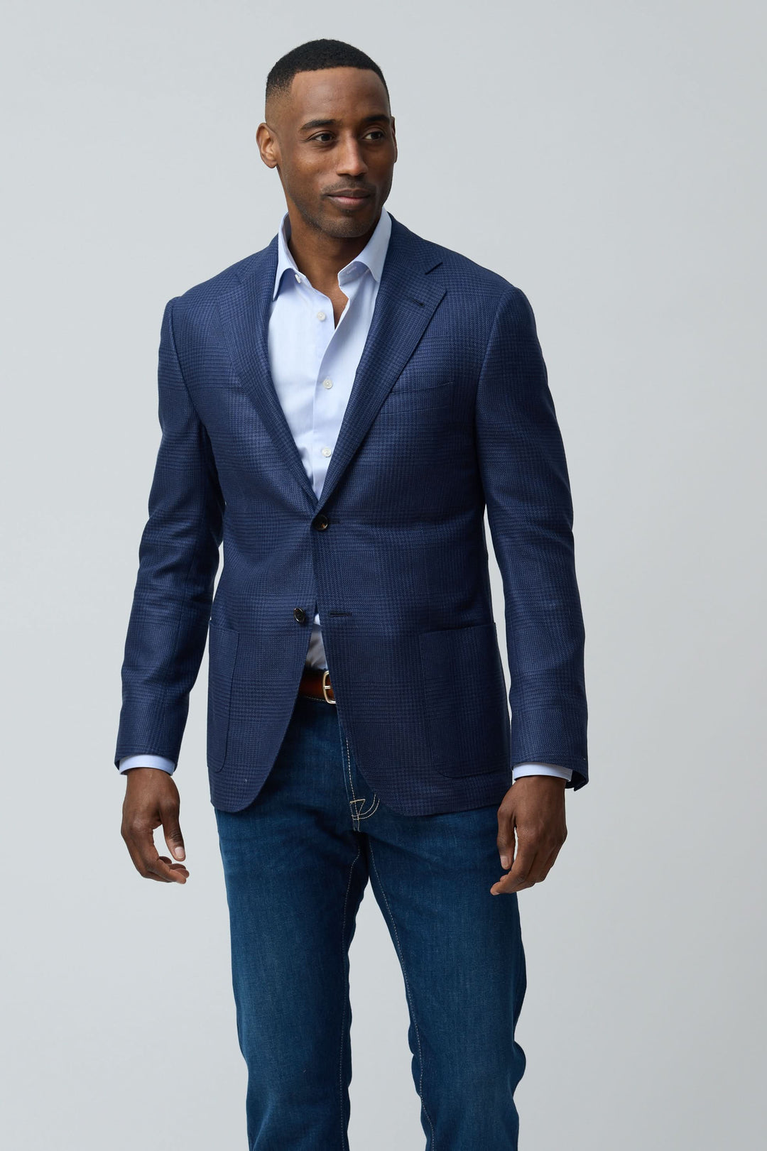 Homme portant un veston structuré à motif subtil avec une coupe moderne et élégante, associé à un style décontracté avec jean.