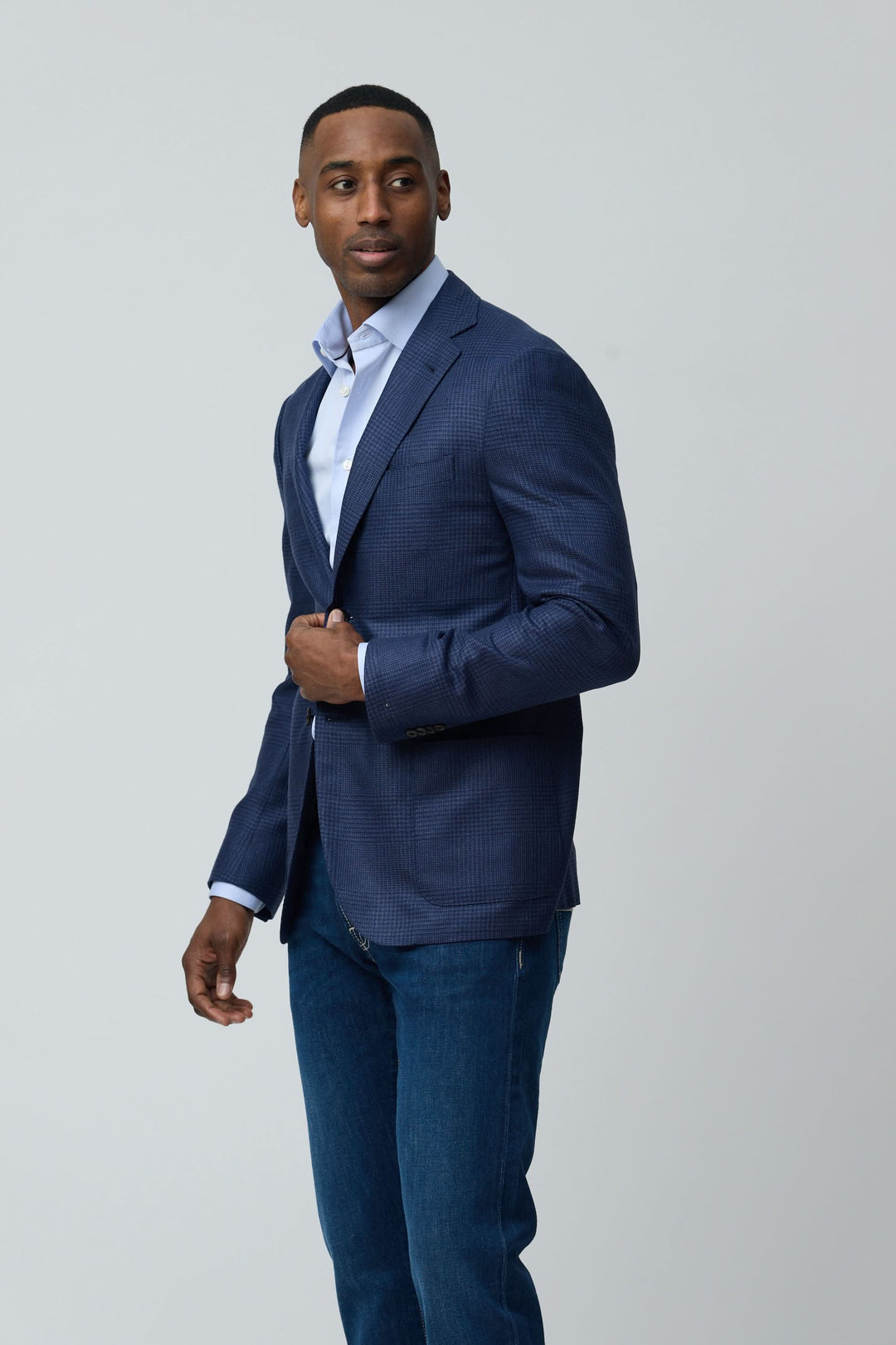 Homme portant un veston structuré à motif subtil en tissu texturé pour un look moderne et raffiné, avec une chemise et un jean.