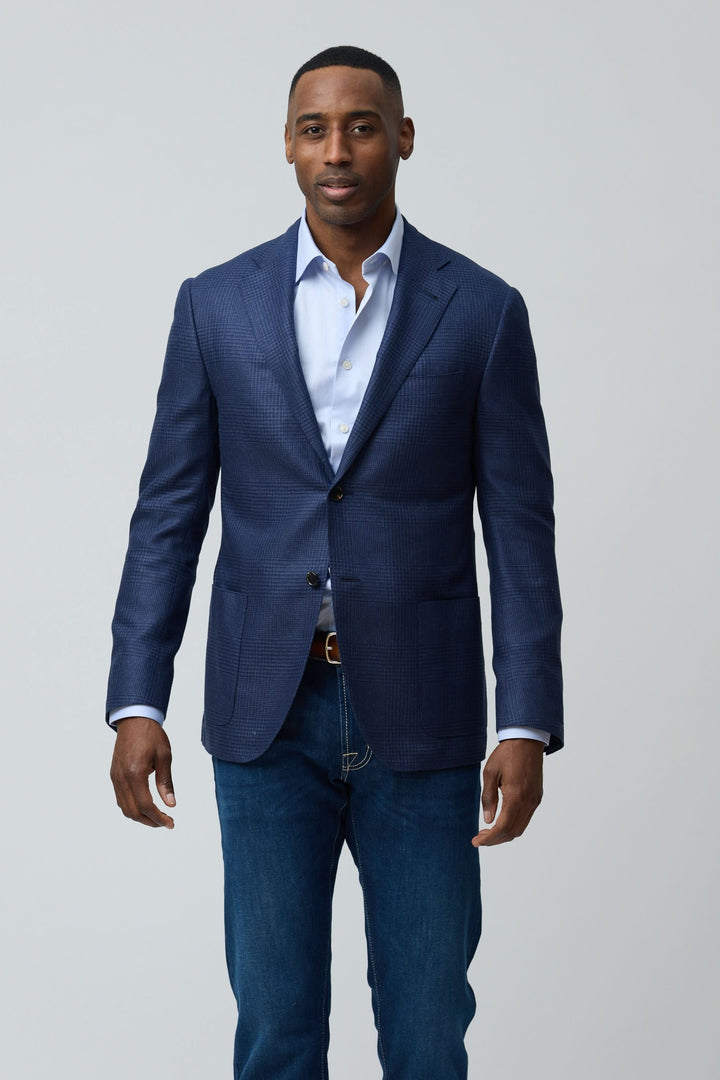 Homme portant un veston structuré à motif subtil, coupe moderne, parfait pour un look décontracté chic avec jean.