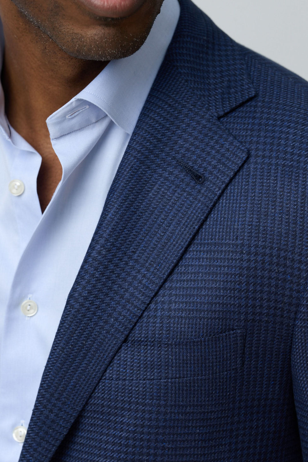 Veston structuré à motif subtil avec tissu texturé, coupe moderne, et détails élégants, porté sur une chemise blanche.