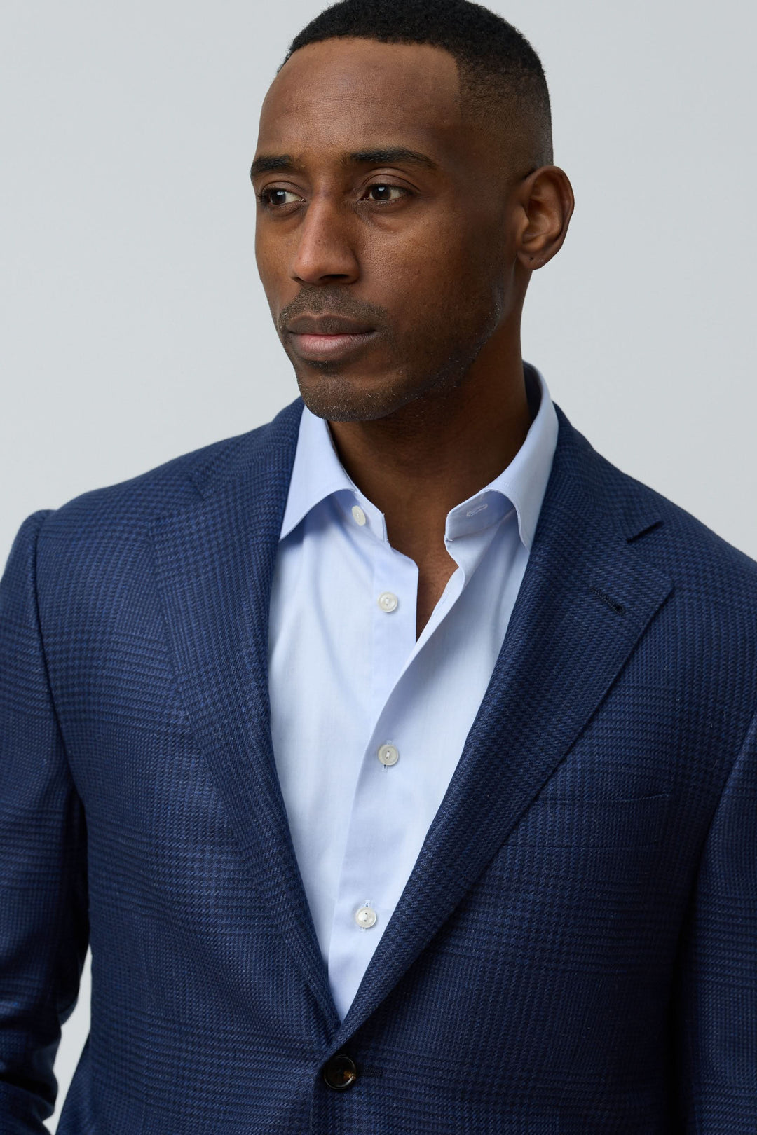 Homme portant un veston structuré à motif subtil avec chemise blanche, style moderne et raffiné