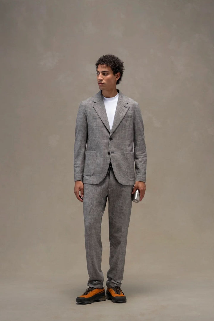 Homme portant un veston texturé, élégant costume gris avec t-shirt blanc, chaussures modernes. Focus sur le veston texturé.