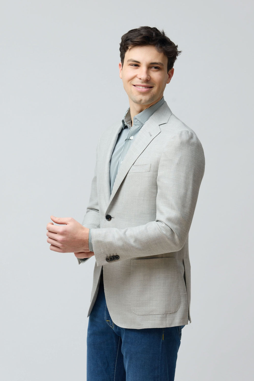 Homme portant un veston texturé en laine, soie et lin, coupe ajustée, couleur grise, style élégant et contemporain.