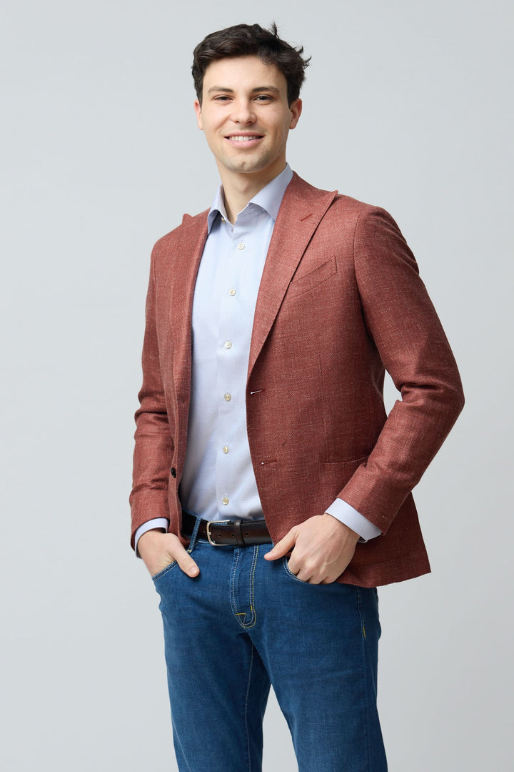 Homme portant un veston texturé en laine, soie et lin rouge, style décontracté chic.