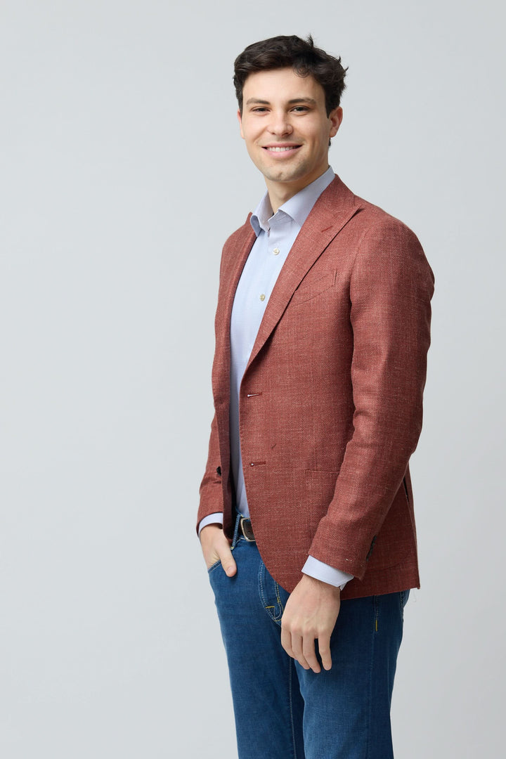 Homme portant un veston texturé en laine, soie et lin de couleur terracotta, style décontracté chic, coupe ajustée, sur chemise bleue.