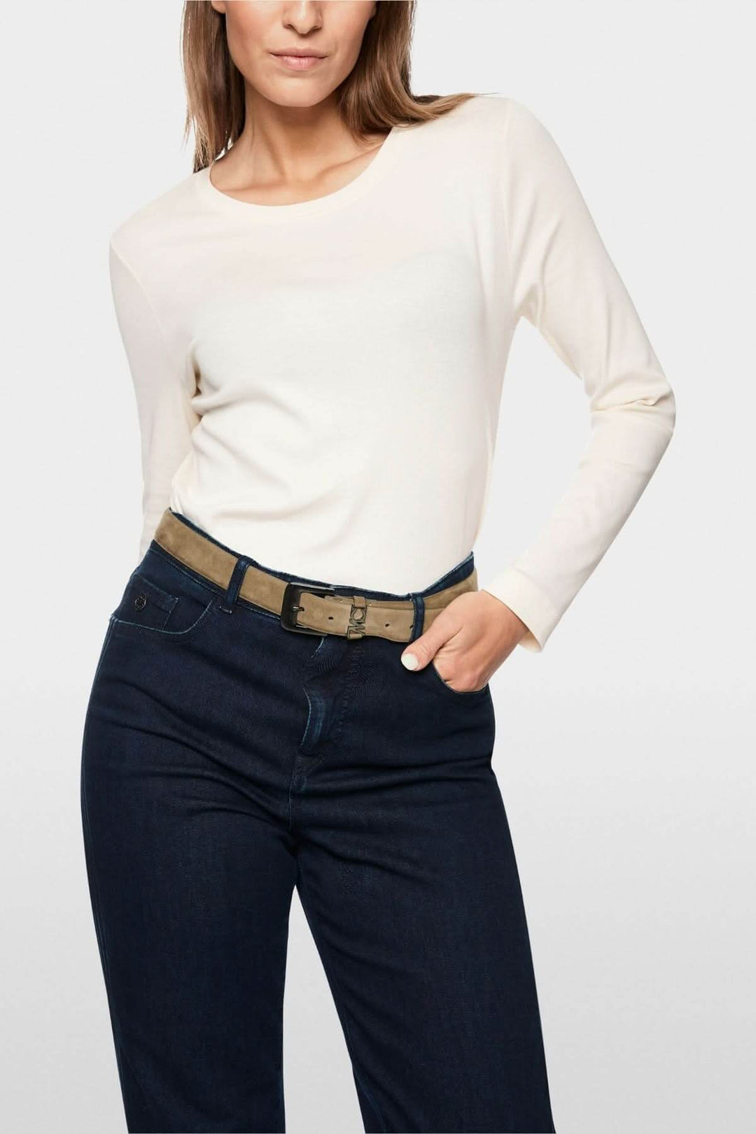 Femme portant un chandail unie à manches longues en couleur neutre, avec un jean foncé, mettant en valeur une tenue chic et minimaliste.