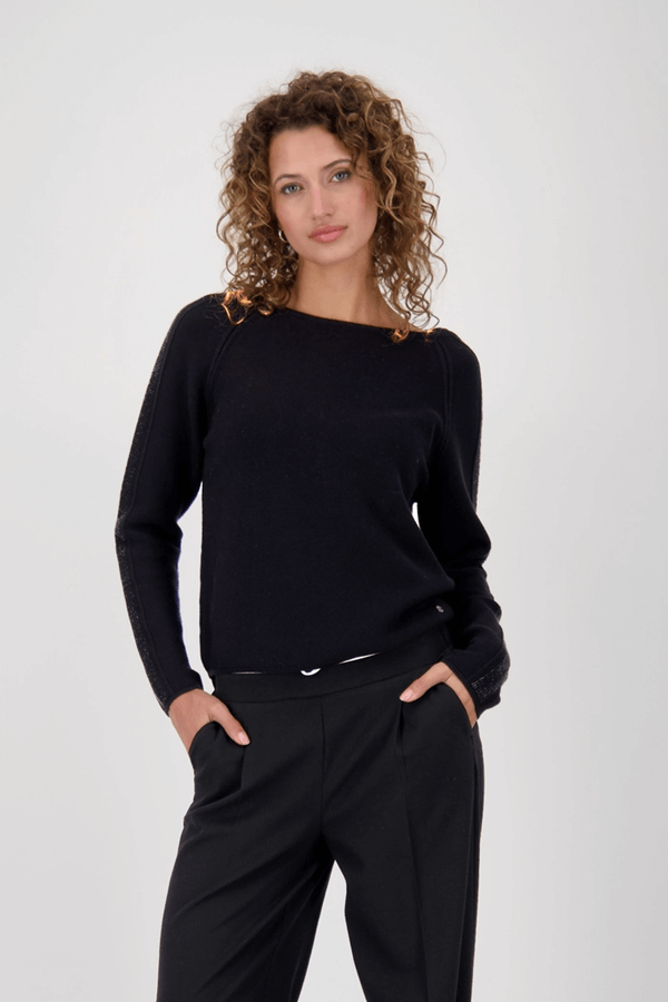 Femme portant un chandail avec des accents décoratifs, manches longues et coupe droite élégante, look chic pour toutes occasions.