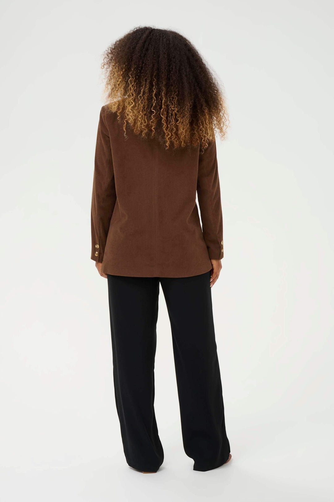 Femme portant le Veston Kanna en velours côtelé à bouton unique, vue de dos, style élégant pour bureau ou week-end.