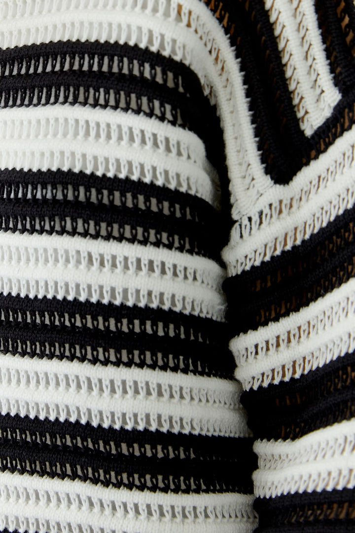 Front view of a beige striped openwork sweater worn by Valérie Simon