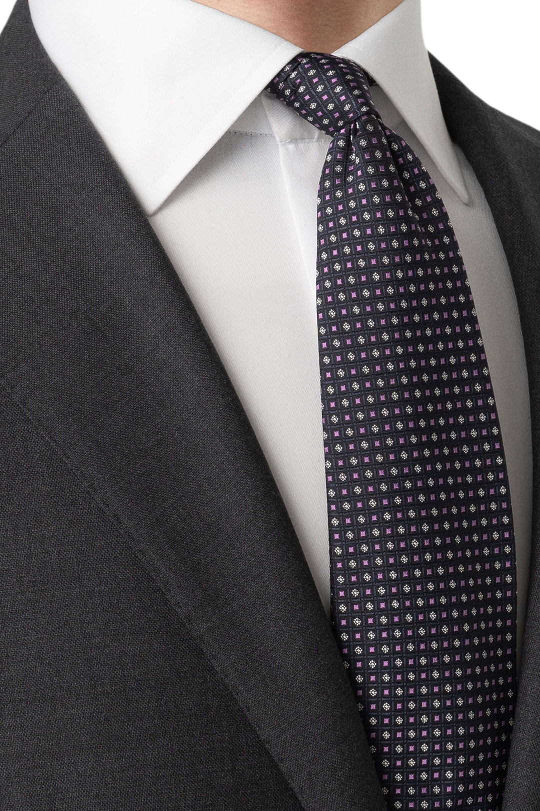 Cravate géométrique en satin aux teintes violet et blanc, portée avec une chemise blanche et un costume sombre.