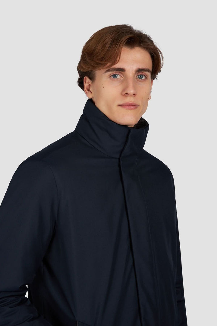 Homme portant un manteau à col montant, élégant et matelassé, couleur sombre, parfait pour un style urbain.