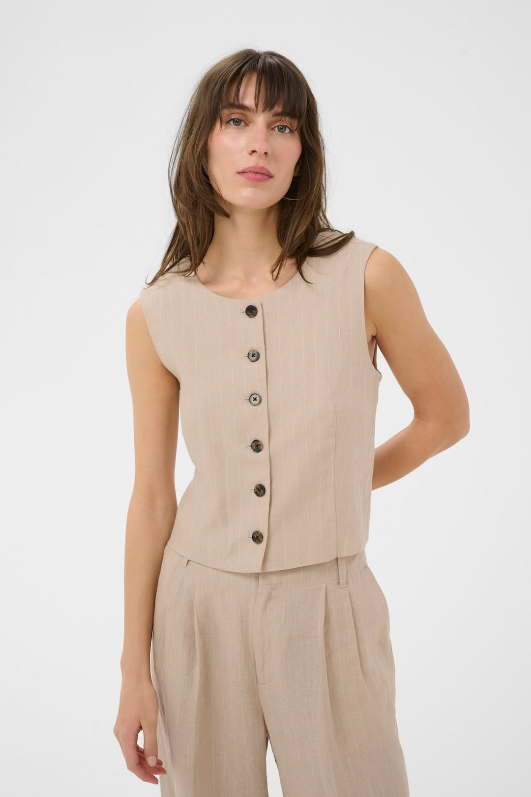 Femme portant une Veste sans manches Azania avec motif rayé et fermeture boutonnée, tenue moderne et élégante pour un look contemporain.